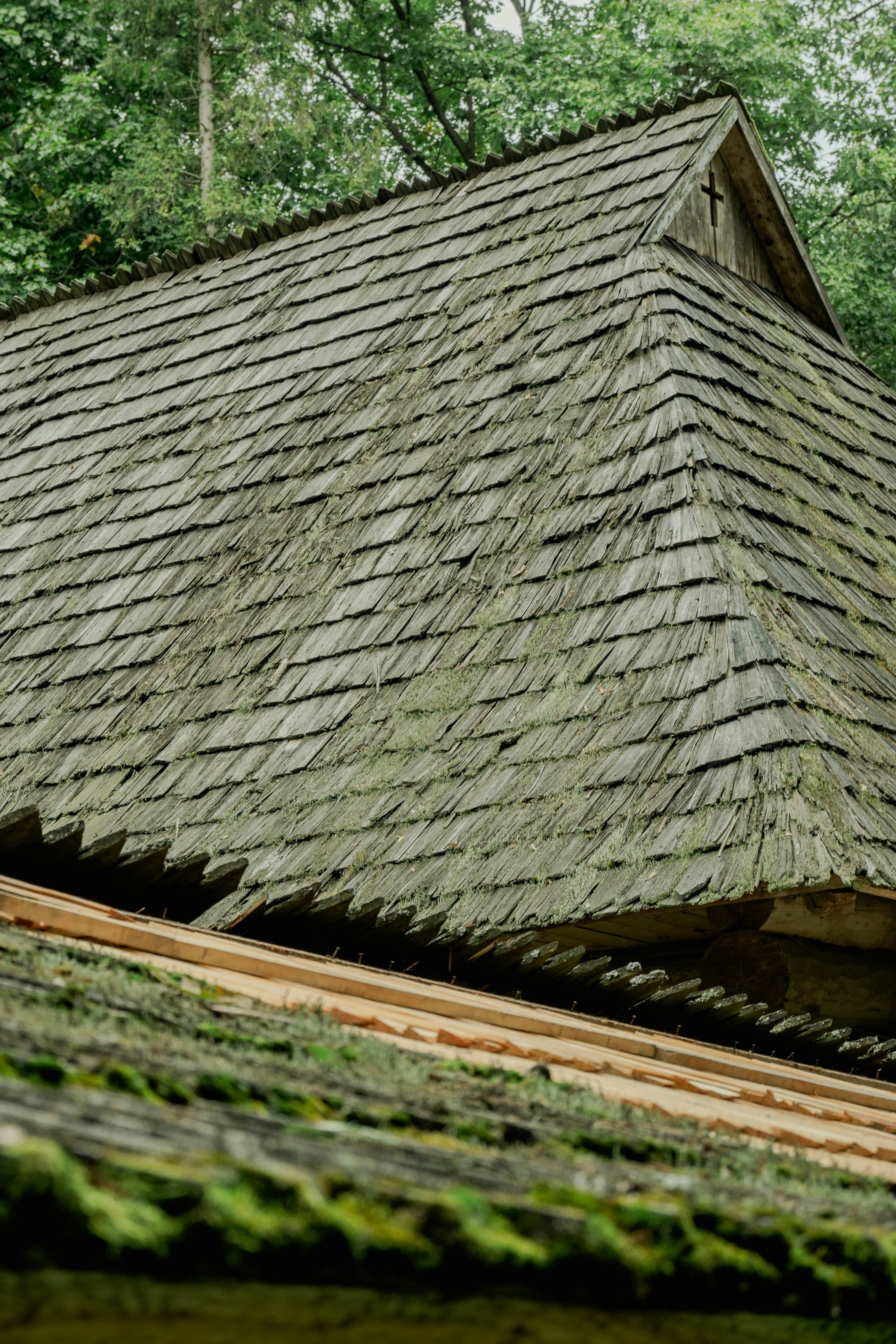 Weathered wooden shingles showing the roof structure beneath