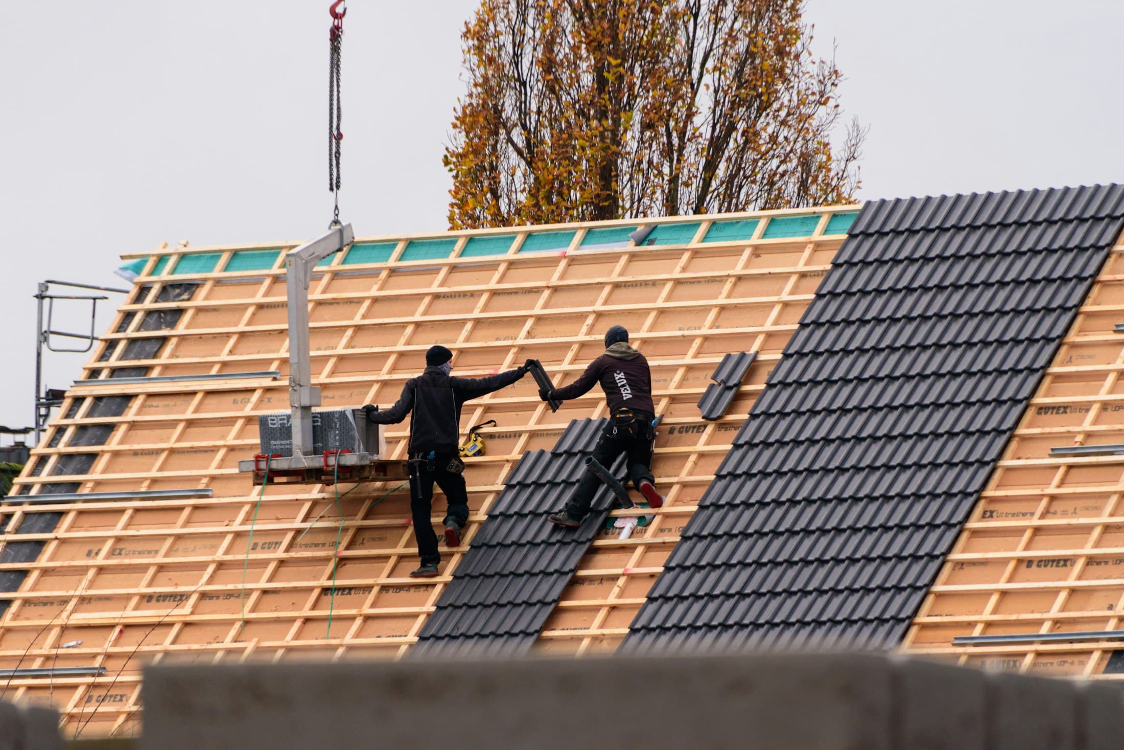 Construction crew installing new roof tiles on a building
