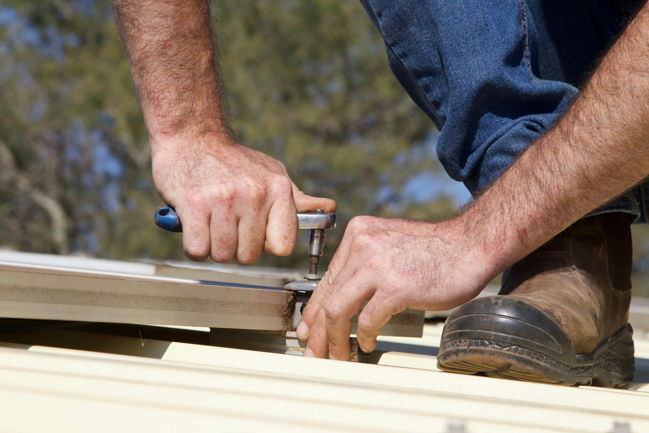Hands fastening metal roofing with a tool
